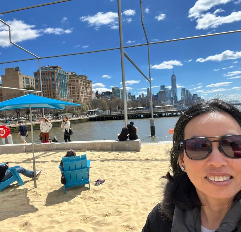 A selfie of a woman in sunglasses at the beach at Gansevoort Peninsula. 