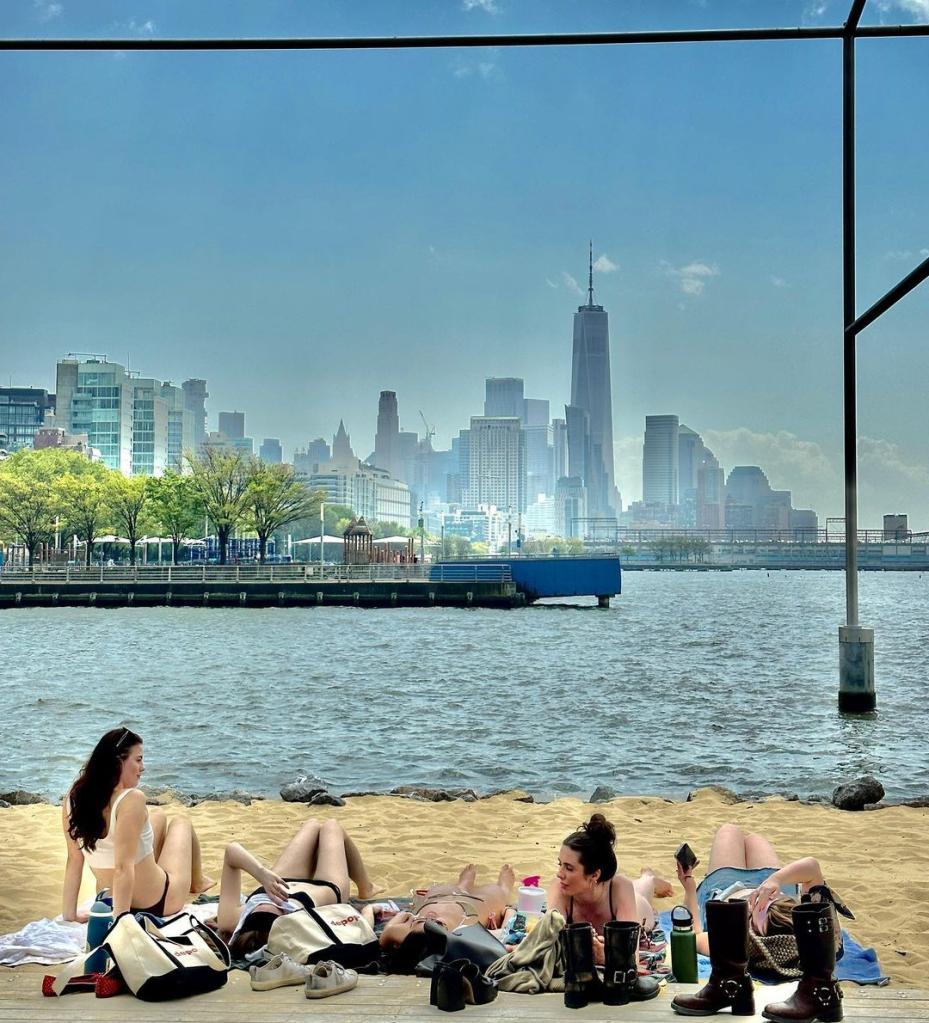 Young women sunbathe in their underewar at Gansevort Peninsula beach, heavy boots and bags in the foreground. 