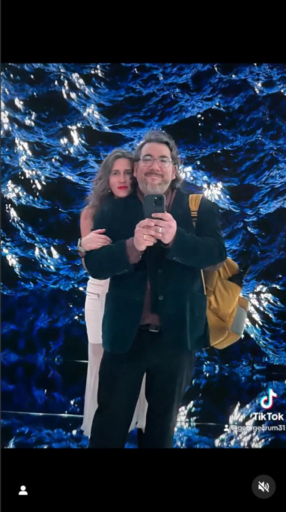 A couple take a selfie in front of ocean wave projections at Mercer Labs. 