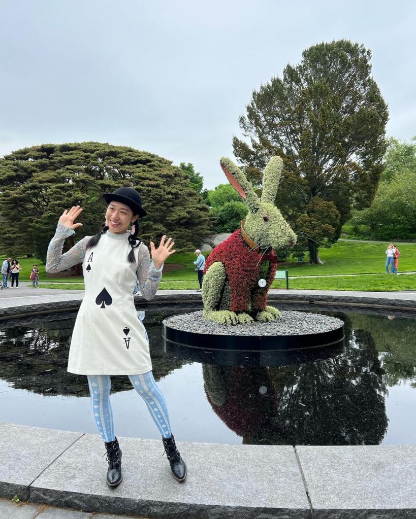 A woman dressed as a card poses in front of a large rabbit topiary at "Wonderland: Curious Nature" at the New York Botanical Garden.