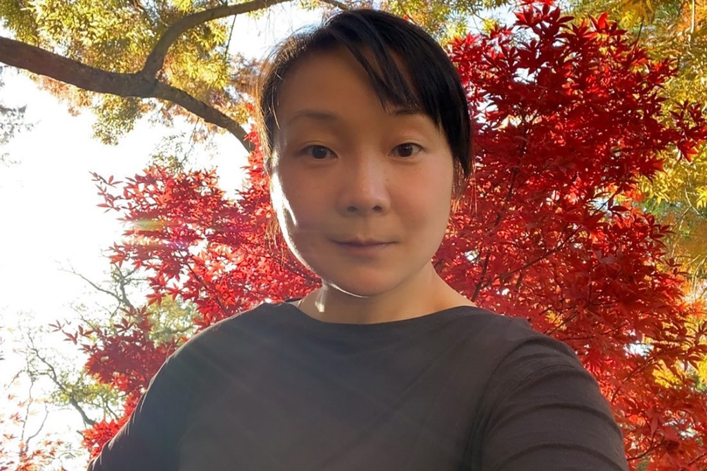 Jie Su can be seen in a selfie with a red tree behind her. 