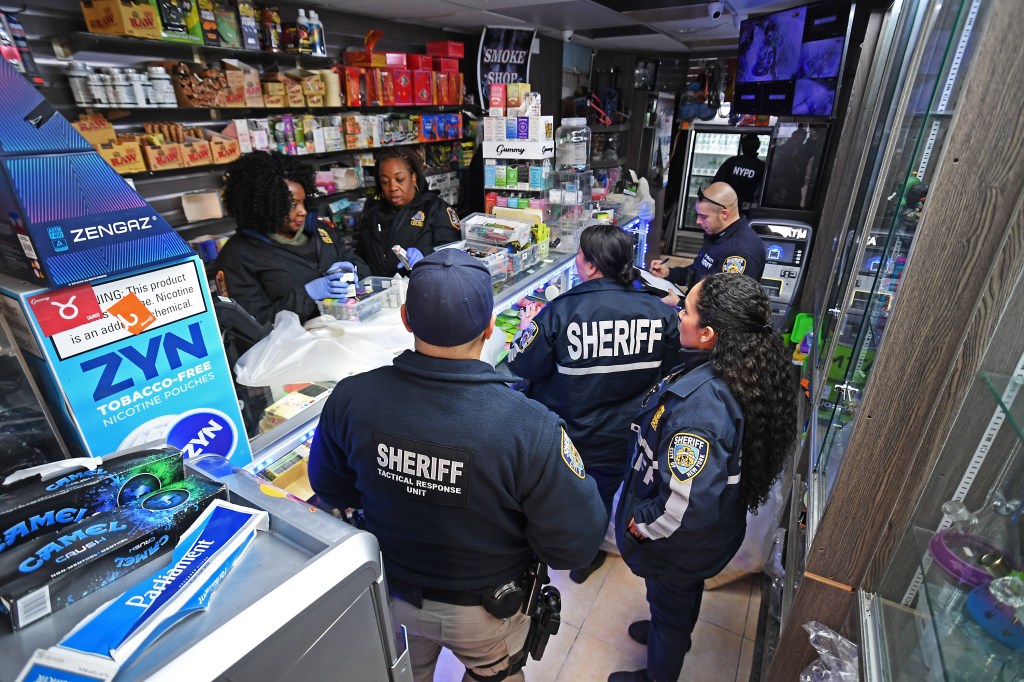 Interior as four NYPD raid an unlicensed pot shop with two women behind the counter. 