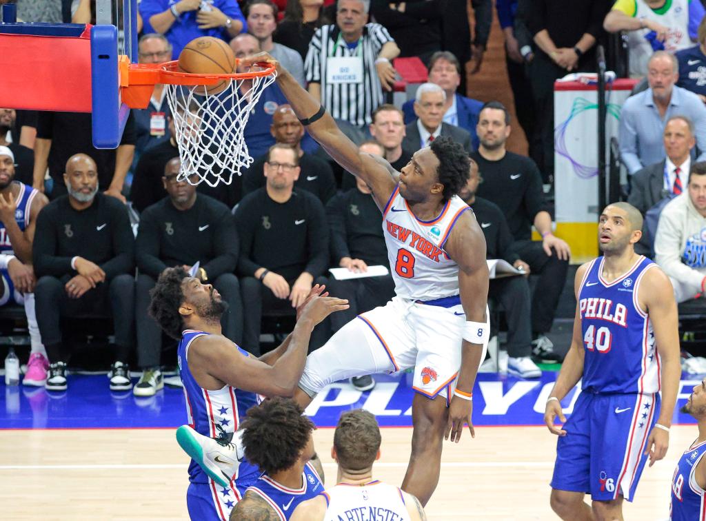 OG Anunoby of the New York Knicks dunking the ball over Joel Embiid of the Philadelphia 76ers during an NBA playoff game.