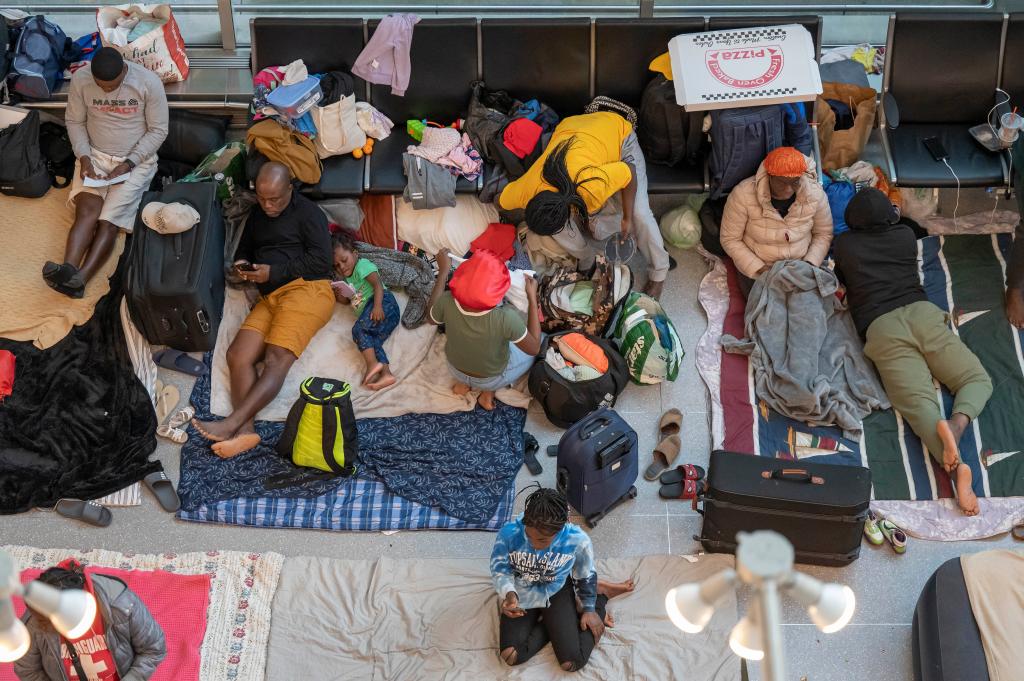 Familes have been forced to sleep on the hard floor with makeshift beds as lights bear down on them all night