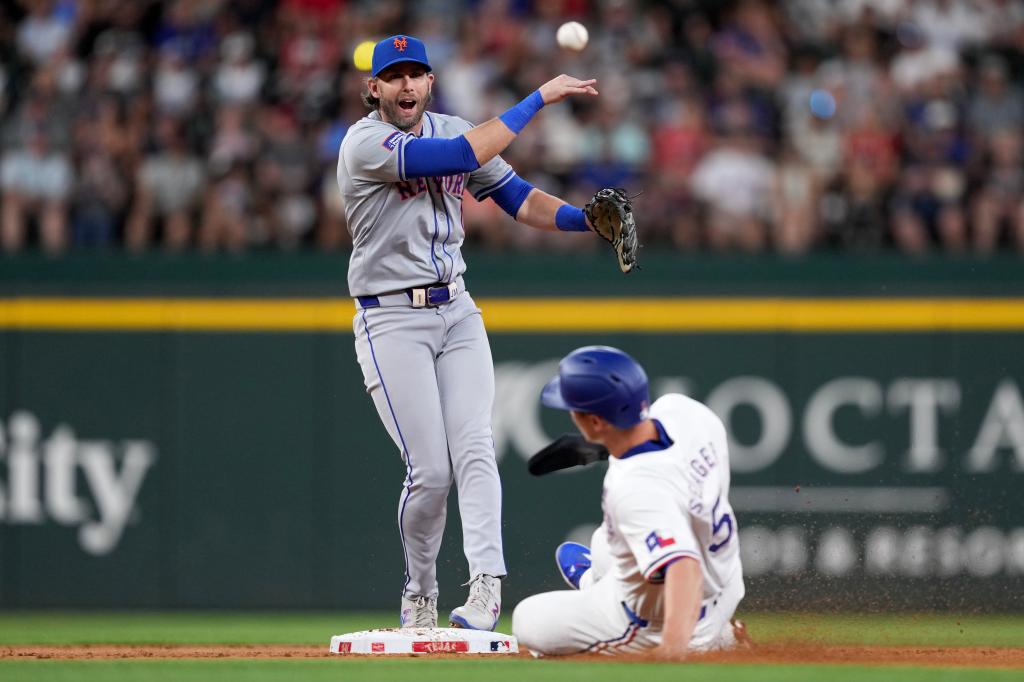 Jeff McNeil of the New York Mets throwing a ball over Corey Seager of the Texas Rangers during a game at Globe Life Field in Arlington, Texas