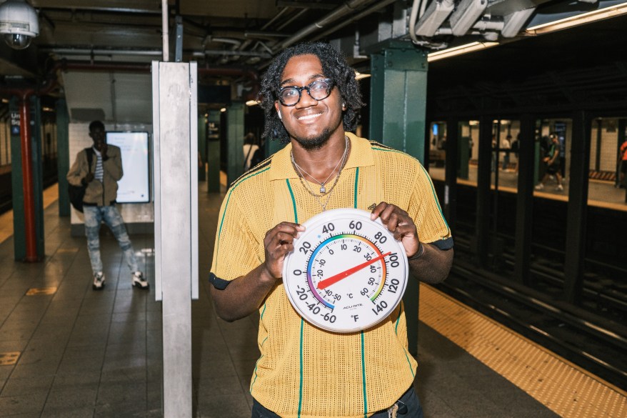 Kobe holds a thermometer reading nearly 100 degrees at the 14 street Union Square subway 