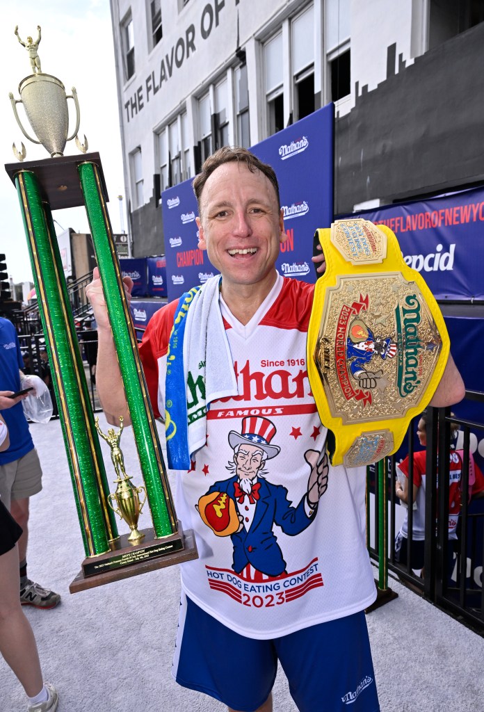 Joey Chestnut holding his trophy and the mustard belt. 
