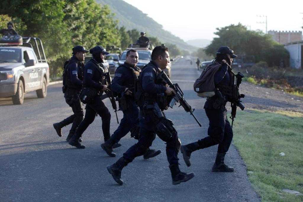 Police officers patrol at a road after fellow police officers were killed during an ambush by suspected cartel hitmen in El Aguaje, in Michoacan state, Mexico