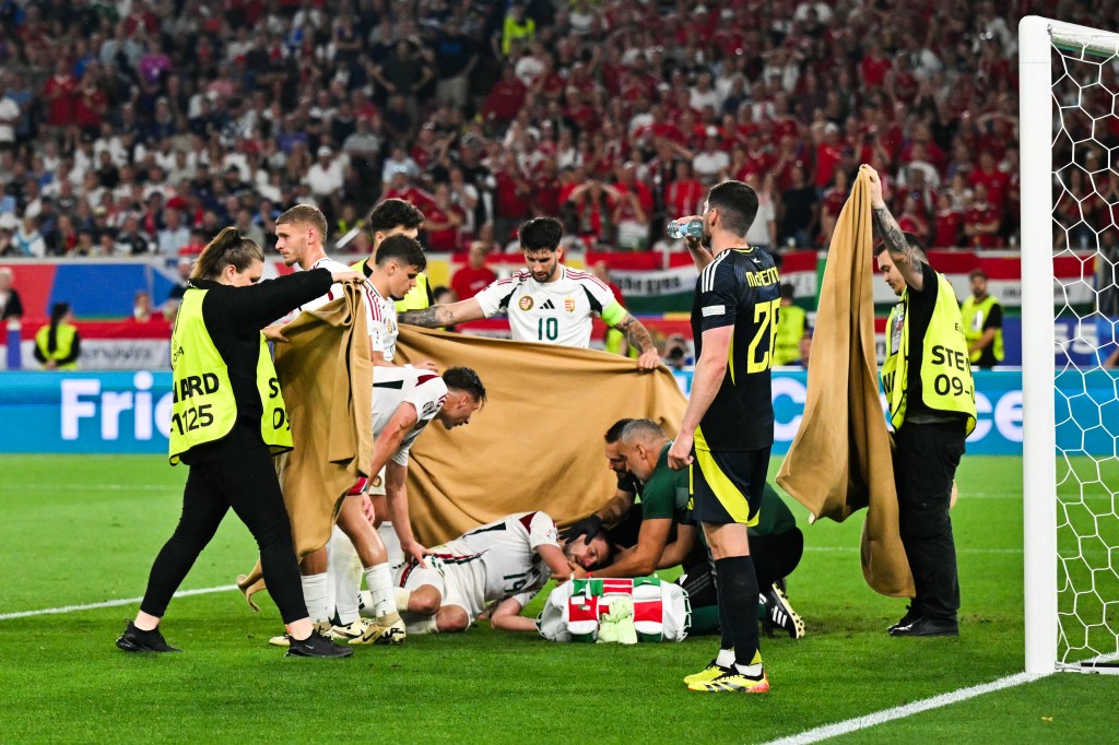Stewards and players holding up a sheet to shield Hungary's footballer Barnabas Varga after a collision during a UEFA Euro 2024 match