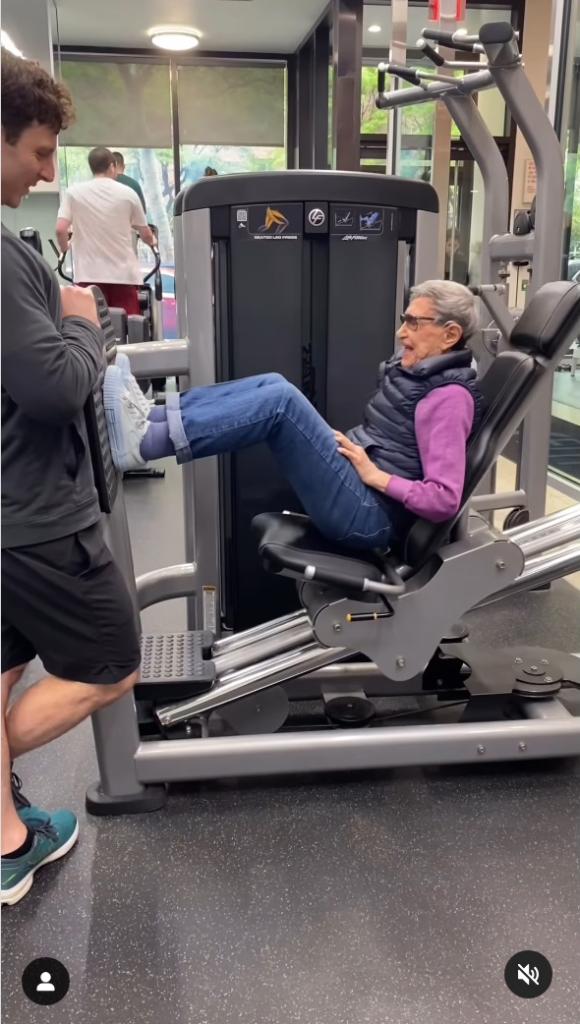 Michelle Cohen does leg presses at a gym with trainer.