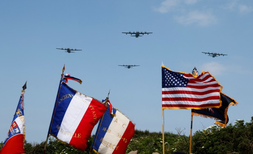 Lockheed C-130 Hercules aircraft overfly flags during a ceremony on "Pointe du Hoc" clifftop in Cricqueville-en-Bessin, northwestern France, on June 5, 2024.