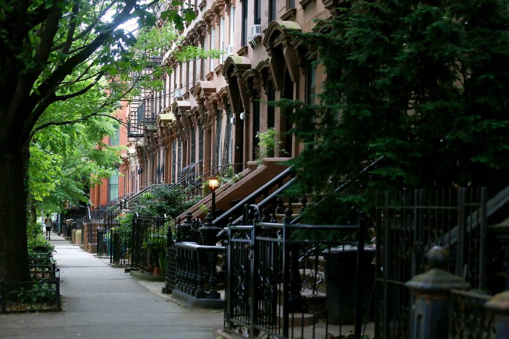 Side view of a series of connected brownstones with stairs.