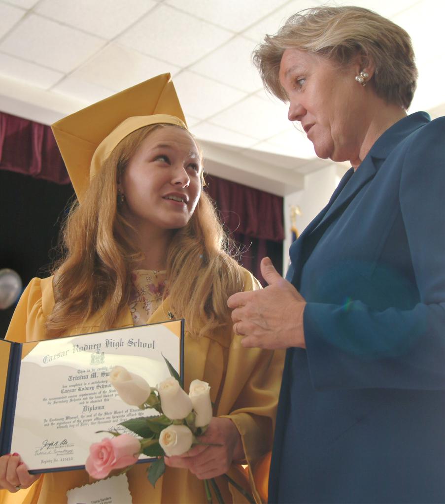 Trisina Sanders in a graduation cap and gown receiving her diploma from Delaware Attorney General M. Jane Brady during a special ceremony