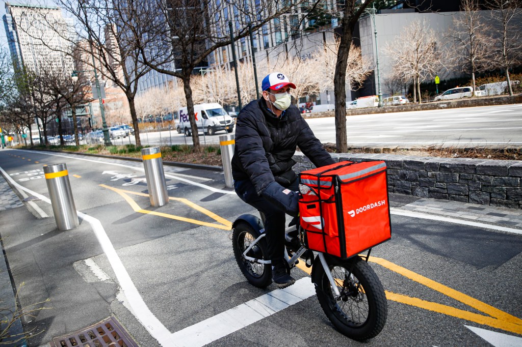 A delivery worker riding his bicycle with a red box on the back along the West Side Highway in New York City