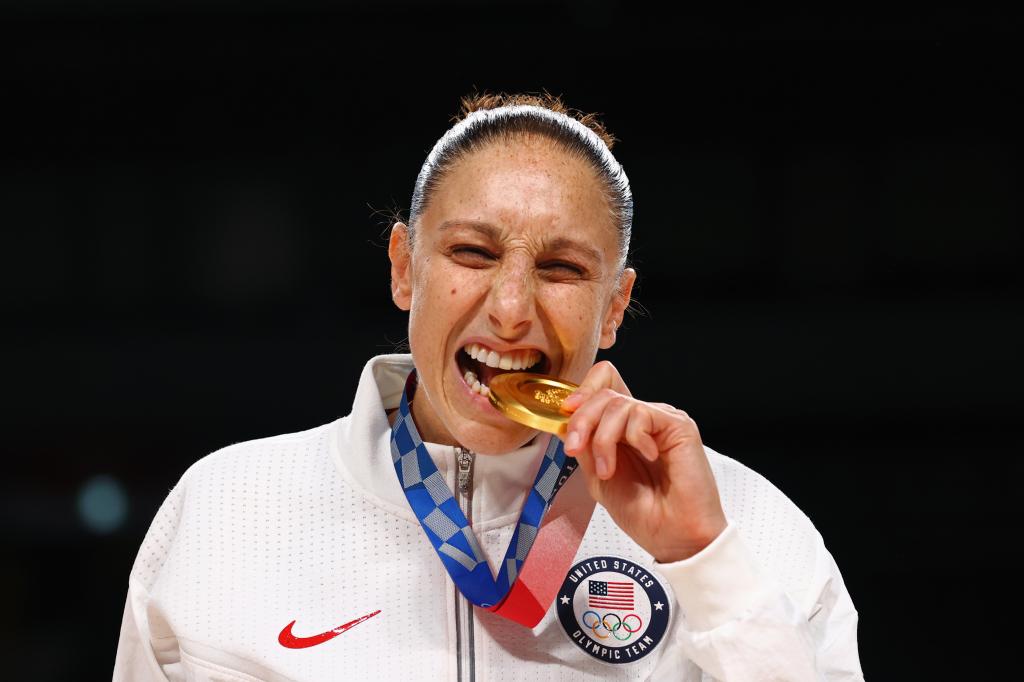 Diana Taurasi bites a Gold medal during the 2020 Olympics.