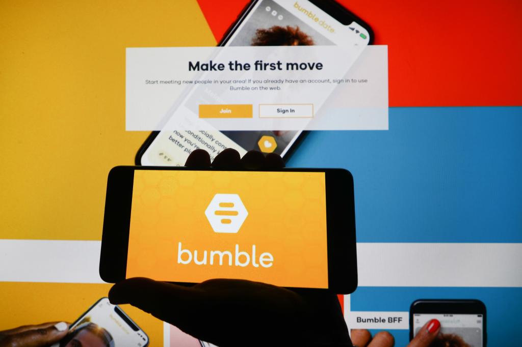 Bumble app logo displayed on a mobile phone screen on Bumble website background, illustrating the growth in online dating services during the Covid-19 pandemic.