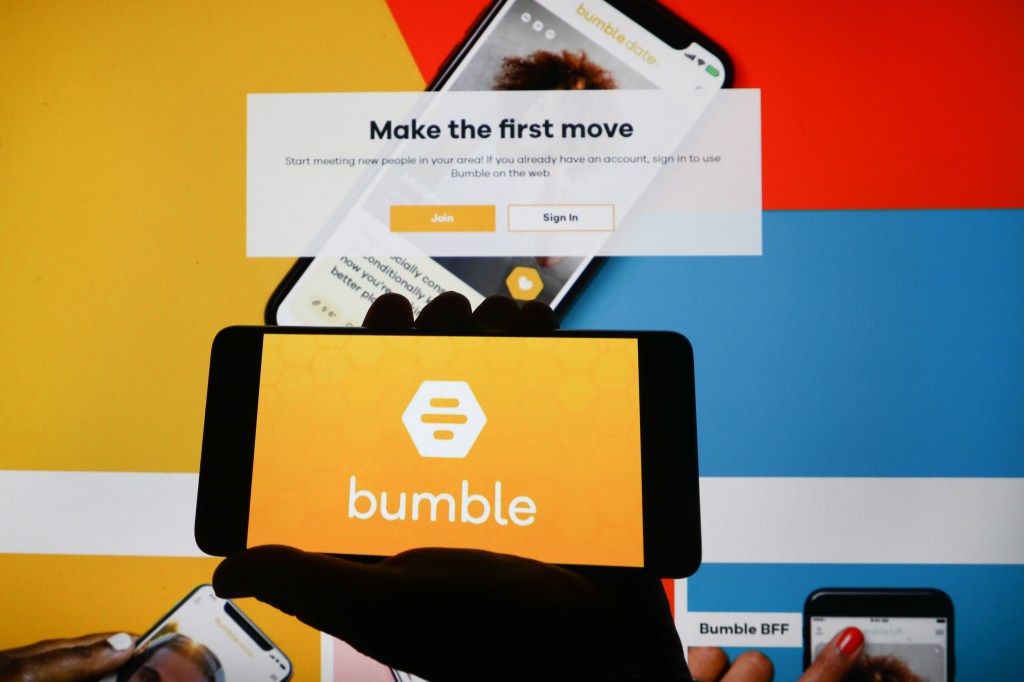 Bumble app logo displayed on a mobile phone screen on Bumble website background, illustrating the growth in online dating services during the Covid-19 pandemic.