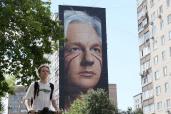 A person walks past a mural depicting WikiLeaks founder Julian Assange on a wall of an apartment building