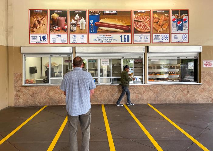 Man standing in front of the outdoor food court area at Costco in the Camino Real Marketplace Shopping Center, Goleta, California.