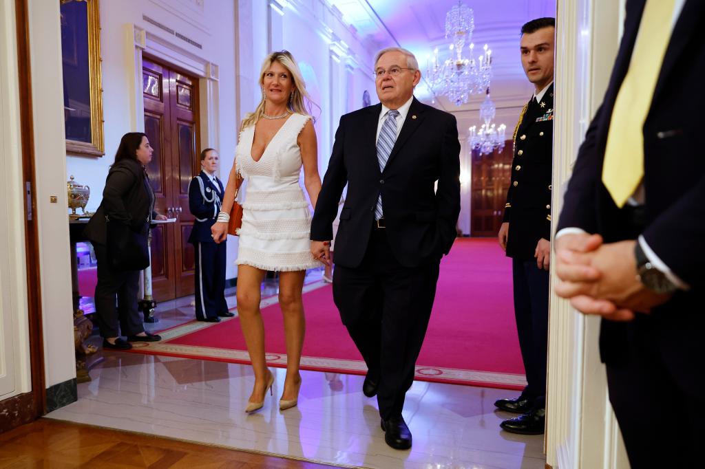 Nadine Arslanian and Robert Menendez hold hands as they walk down a hallway in the White House.