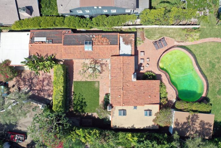 Aerial view of Marilyn Monroe's historic Spanish Colonial-style house in Brentwood, California, with a pool and lawn.