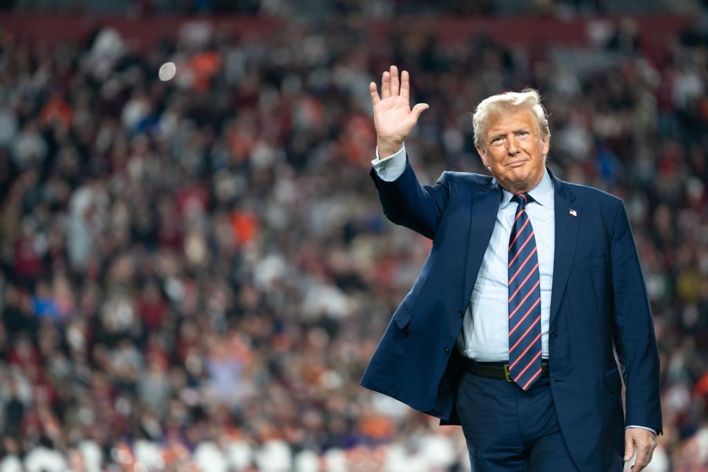 Former U.S. President Donald Trump waving to the crowd during halftime at the Palmetto Bowl in Columbia, South Carolina on November 25, 2023.