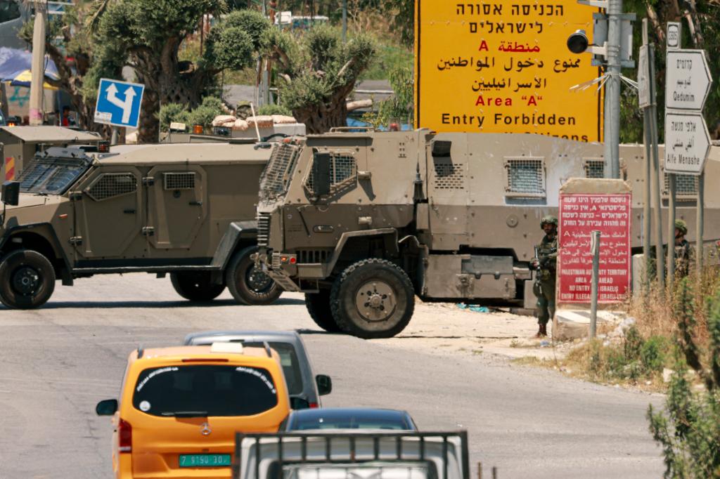 Israeli army vehicles close off the entrance to the West Bank city of Qalqilya after an Israeli civilian was shot and killed.