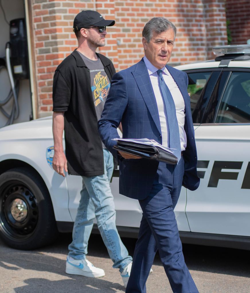 Justin Timberlake with his attorney Edward Burke Jr., leaving arraignment in Sag Harbor, charged with DWI, walking past a police car.