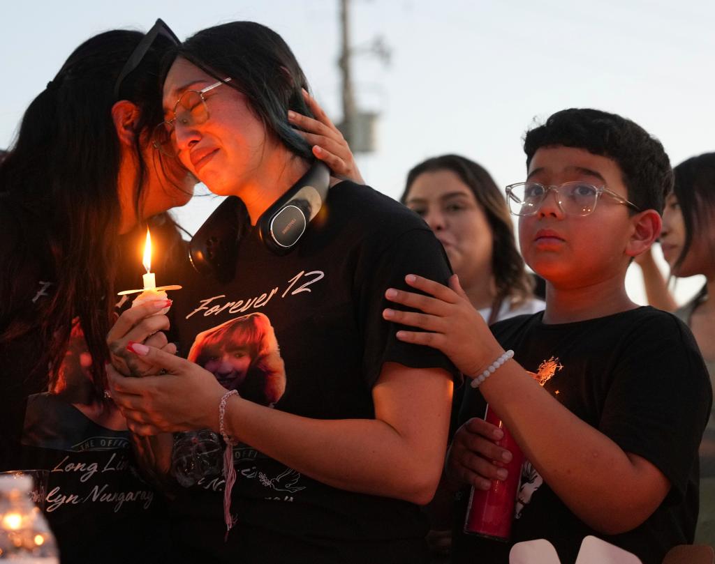 Jocelyn Nungaray's mother, Alexis, is seen holding a candle and being consoled at a vigil for her daughter.