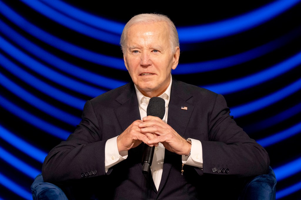 President Joe Biden seated at a campaign event with a microphone in Los Angeles, pausing amidst cheers in June 2024