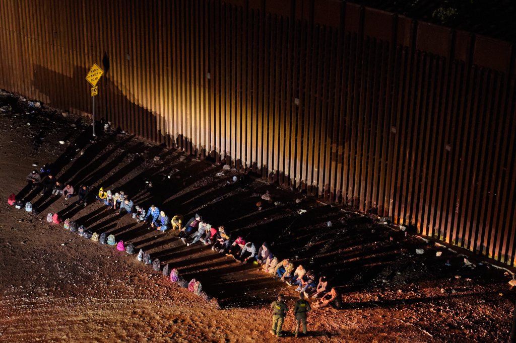 Migrants who crossed the border turn themselves in to Border Patrol agents in the Tucson sector, where they're sitting in lines next to the border wall.