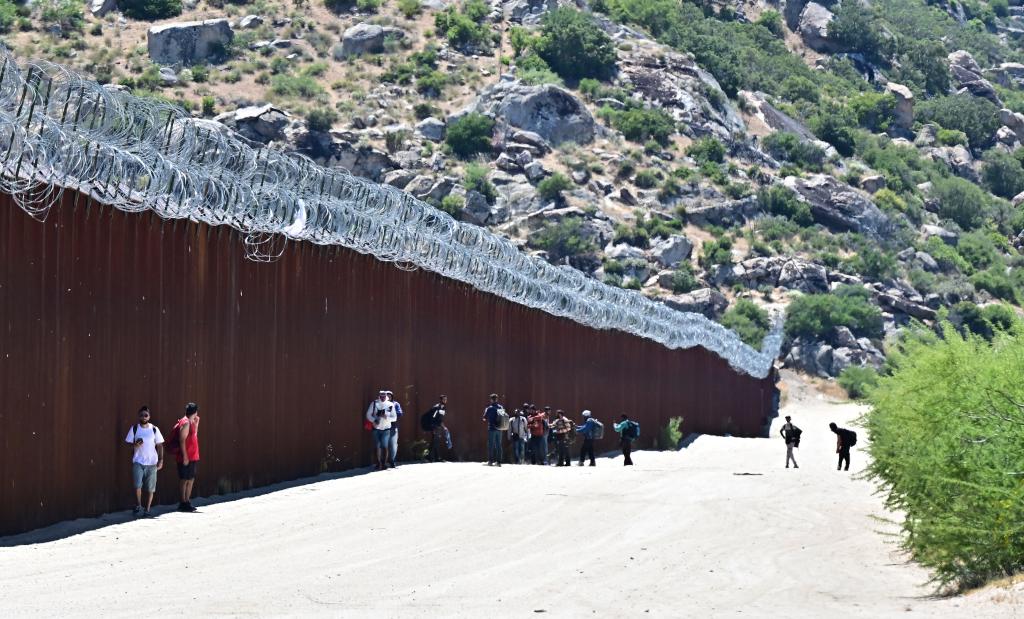 Migrants from various countries walking into the US beside the US-Mexico border wall at Jacumba Hot Springs, California.