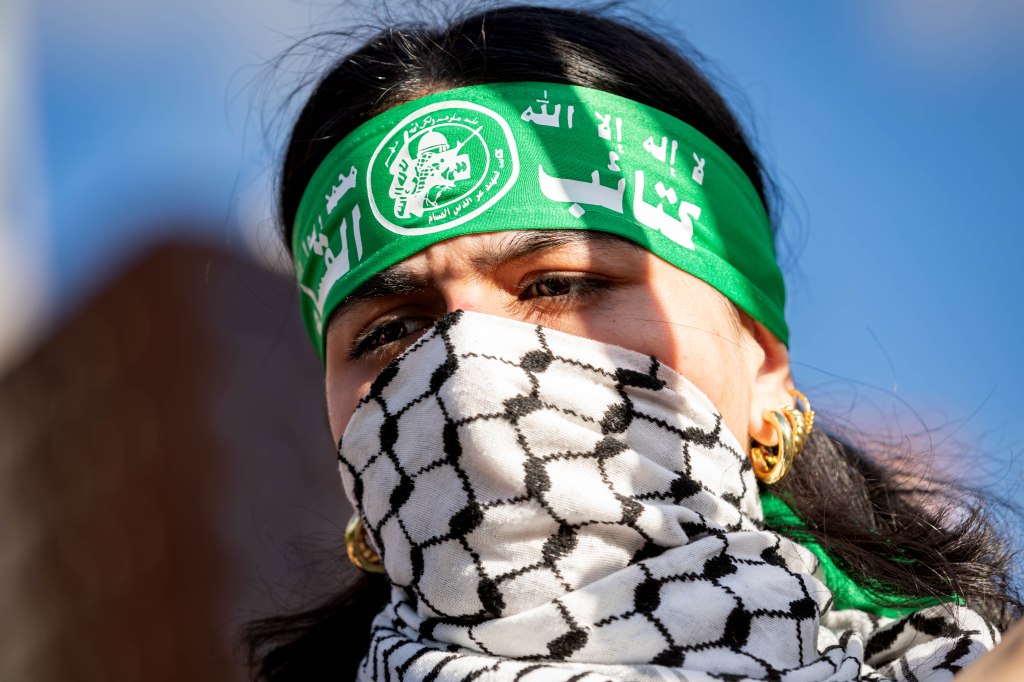Pro-Palestine protester wearing a keffiyeh as a mask and a green bandana
