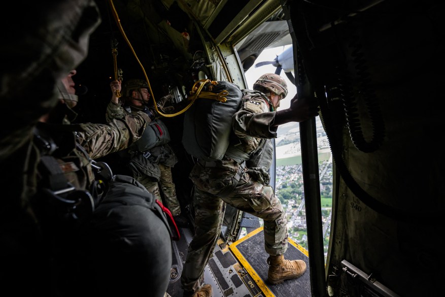 US and Belgian military paratroopers jump from a Lockheed C-130 Hercules aircraft chartered and navigated by US crew, as it flies over Normandy.