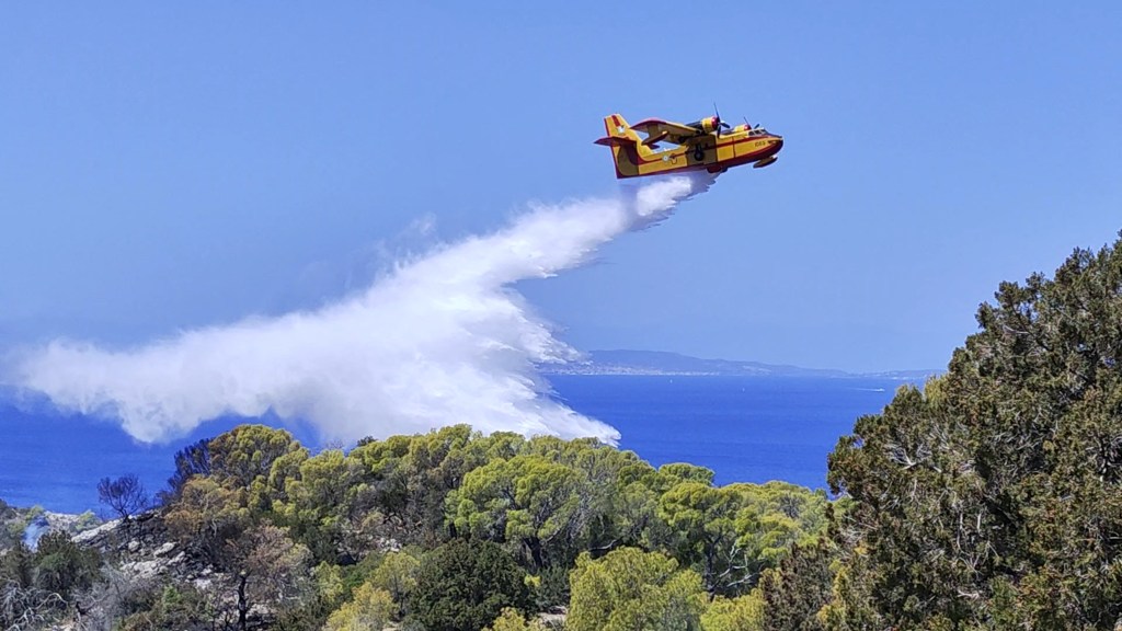 A firefighting plane dropping water of an area of the island affected by the forest fire.