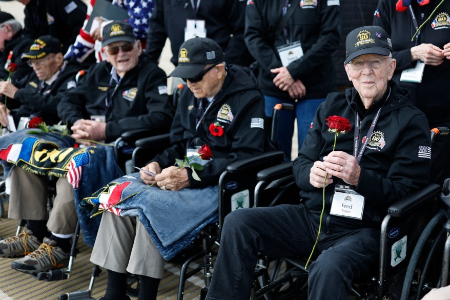 American WW II veteran Fred Taylor, right, and others hold roses during a wreath-laying ceremony at Utah Beach, Wednesday, June 5, 2024.