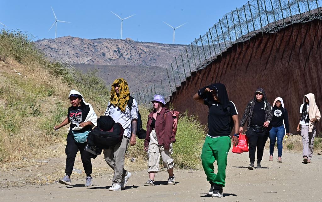 Migrants from various countries walking on the US side of the border wall in Jacumba Hot Springs, California under intense heat