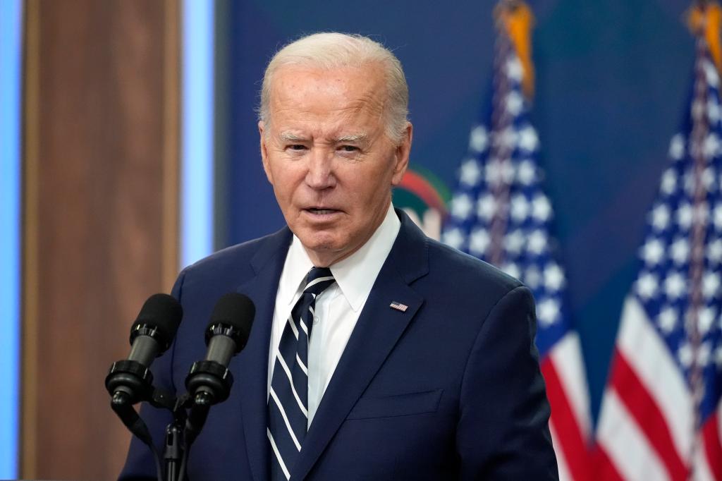 President Joe Biden speaks before a crowd from a podium.