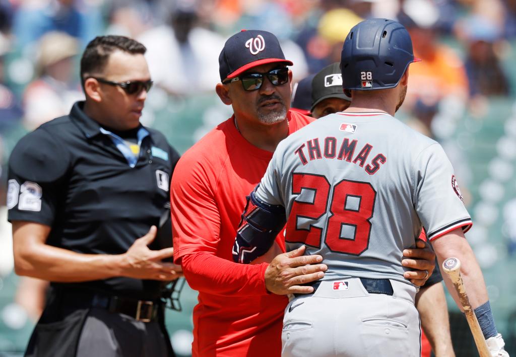 Miguel Cairo #22 of the Washington Nationals tries to direct Lane Thomas #28 away from home plat umpire Emil Jimenez.