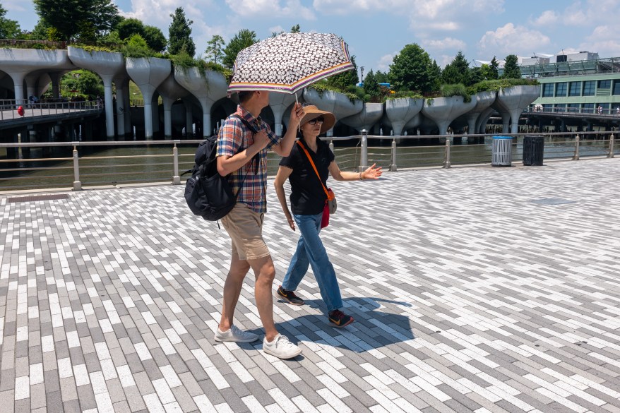 two people walking with an umbrella to block the sun