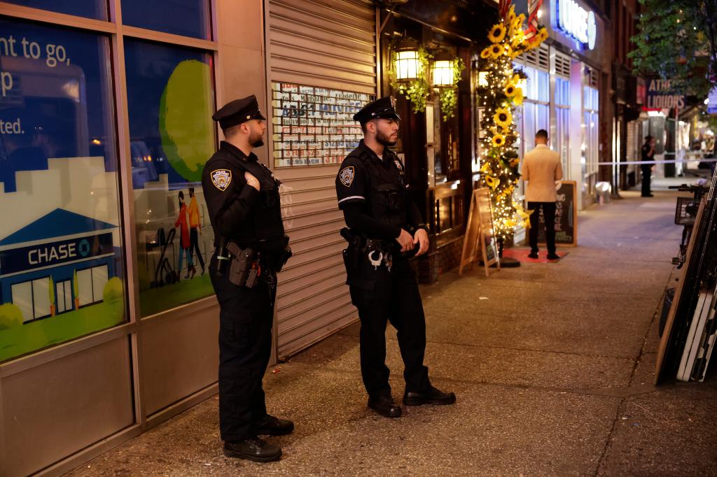 NYPD officers stand near the scene where a woman was stabbed at a Thai Grocery store in Manhattan on Tuesday night.