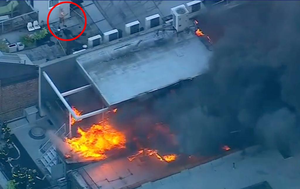 Good Samaritan using a garden hose from neighboring rooftop to help firefighters control a two-alarm fire in a SoHo building