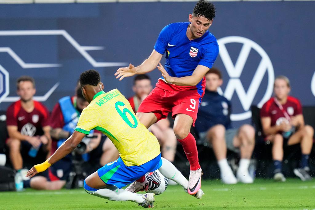 Wendell of Brazil in blue uniform tackling Ricardo Pepi of the United States during the Continental Clasico 2024 game at Camping World Stadium, Orlando, Florida.