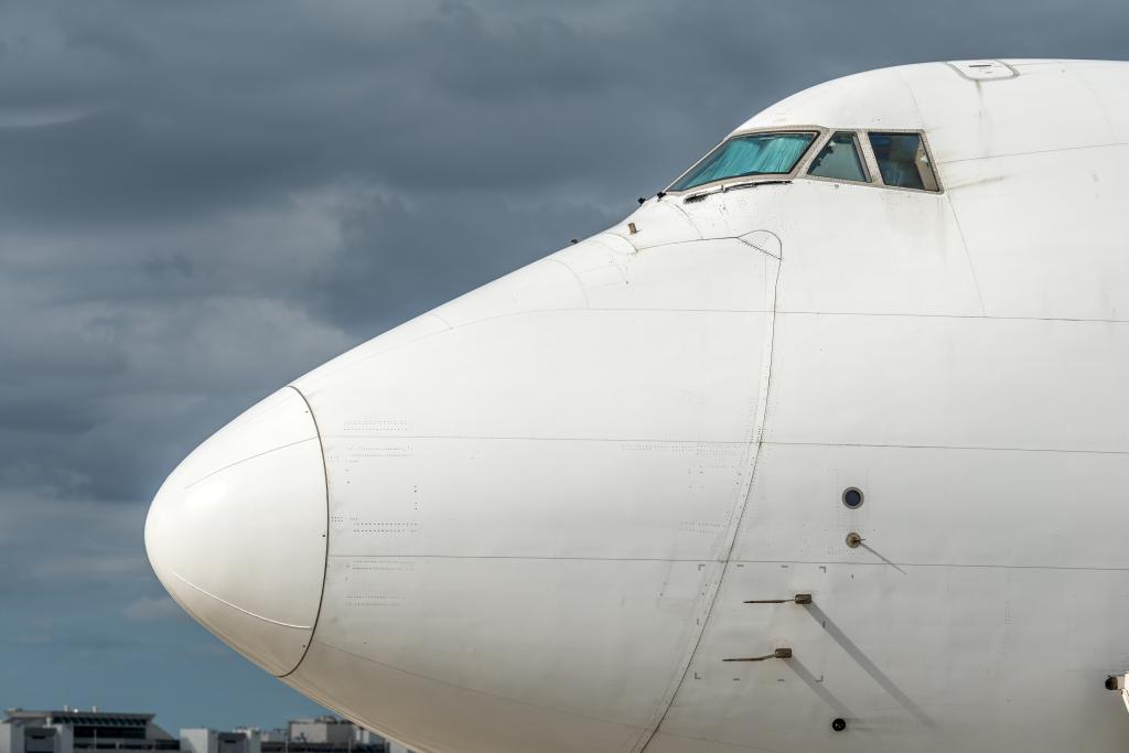 White Boeing 747 cargo plane on an airport runway, view focuses on the nose of the plane