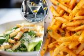 A close up of caesar salad, fries, martinis