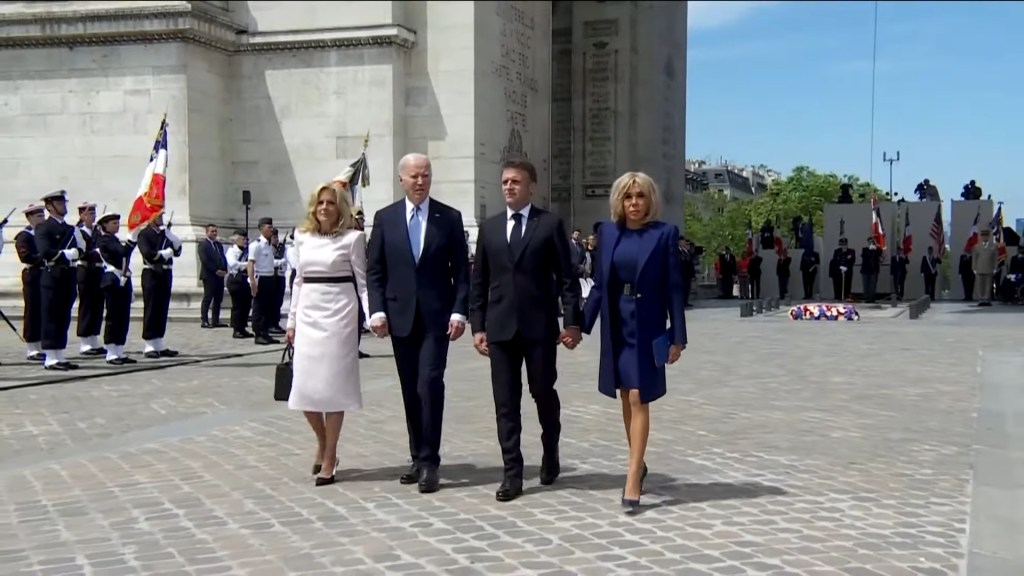 Joe Biden and a group of people walking in a plaza during a press conference about the importance of allyship.