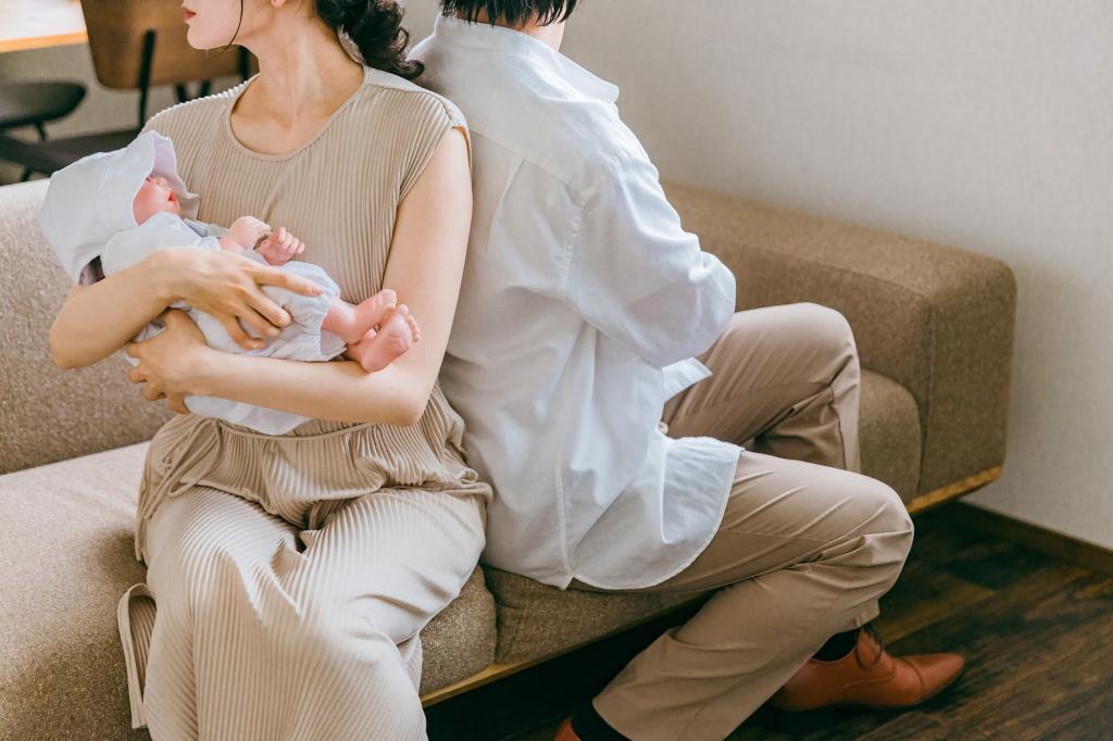 Woman holding baby, sitting back to back with a man