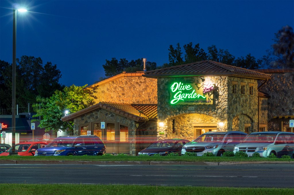 Exterior view of an Olive Garden building with parked cars in front.