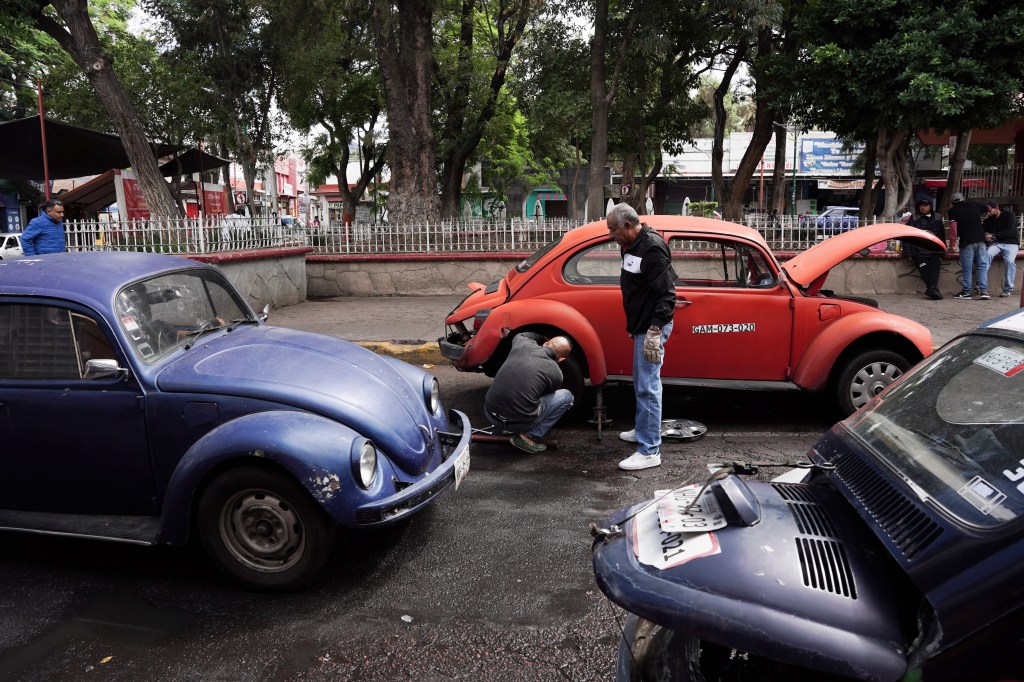 Volkswagen Beetle taxi drivers change a flat tire in the Cuautepec neighborhood of Mexico City