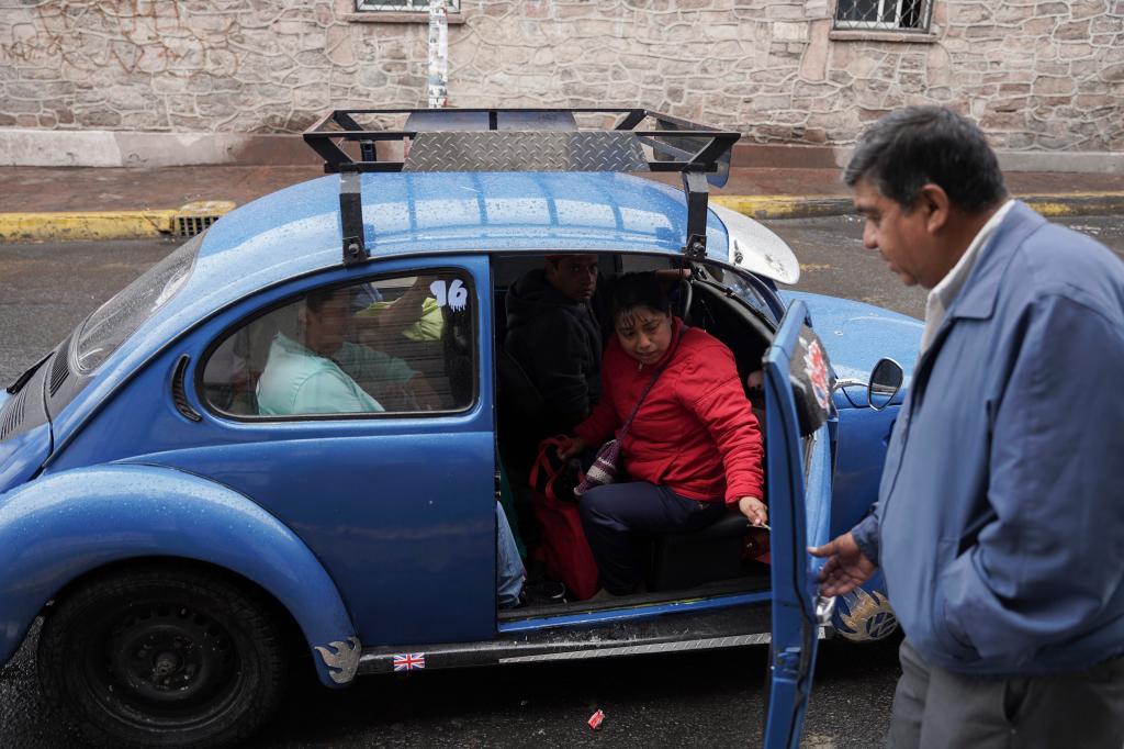 Taxi rank manager Rafael Ortega helps passengers into a Volkswagen Beetle 